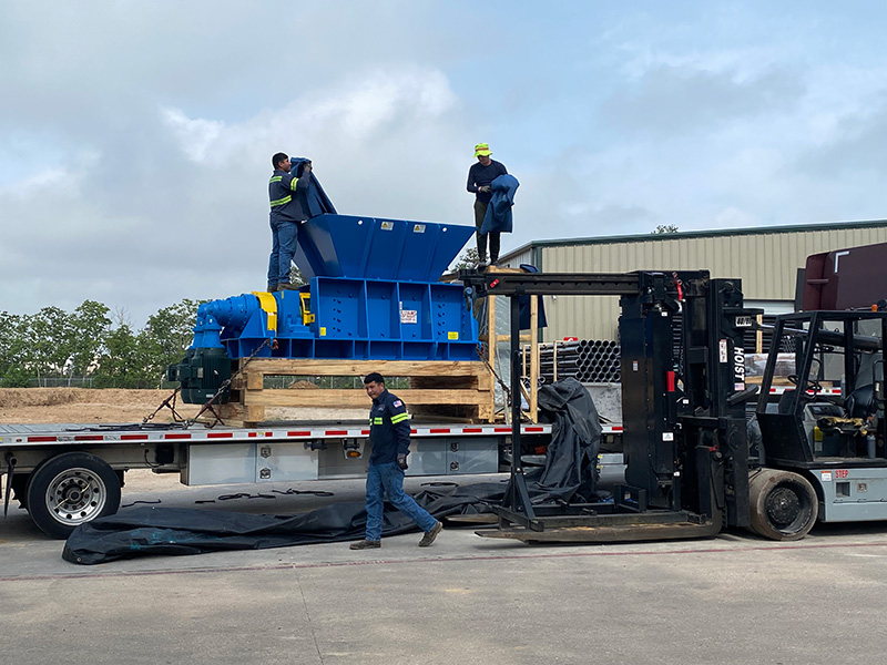 Employees unloading a new Crusher for Champion Fiberglass